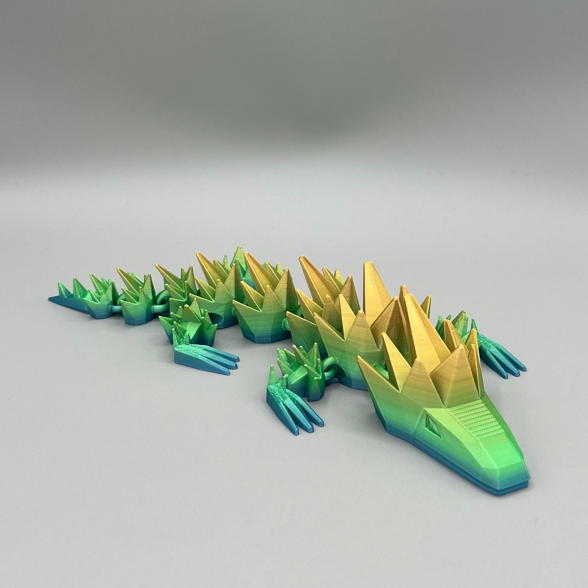Heady Prints 3D printed green and yellow articulated spikey lizard, front view